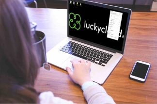 Bird's eye view over the shoulders of a woman. The luckycloud logo can be seen on the screen of a laptop.