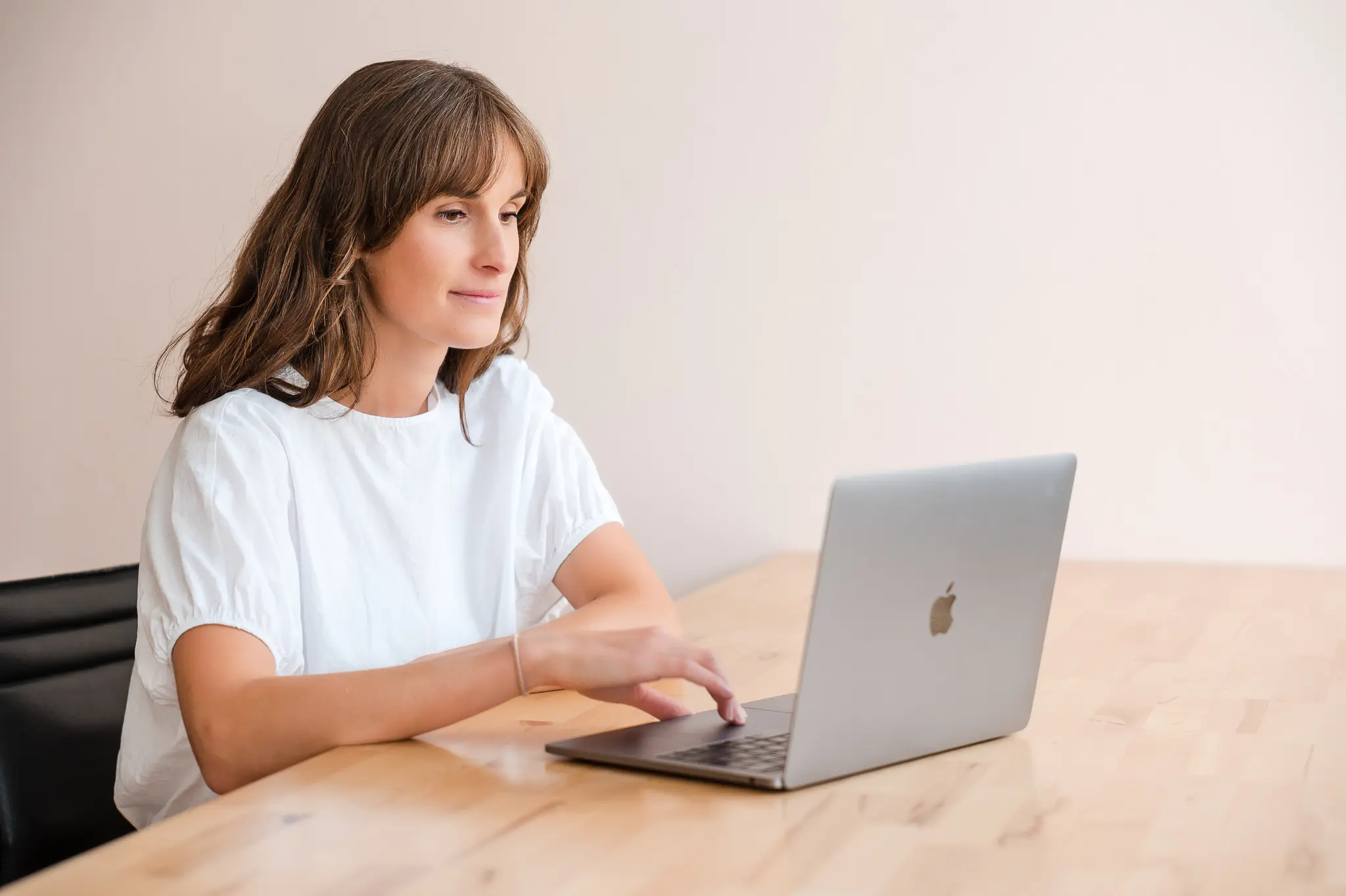 Eine Frau sitzt vor ihrem geoeffneten Laptop.