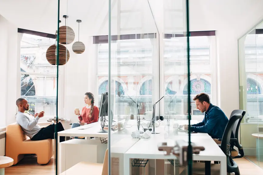 Colleagues work and socialize in a bright, modern office.