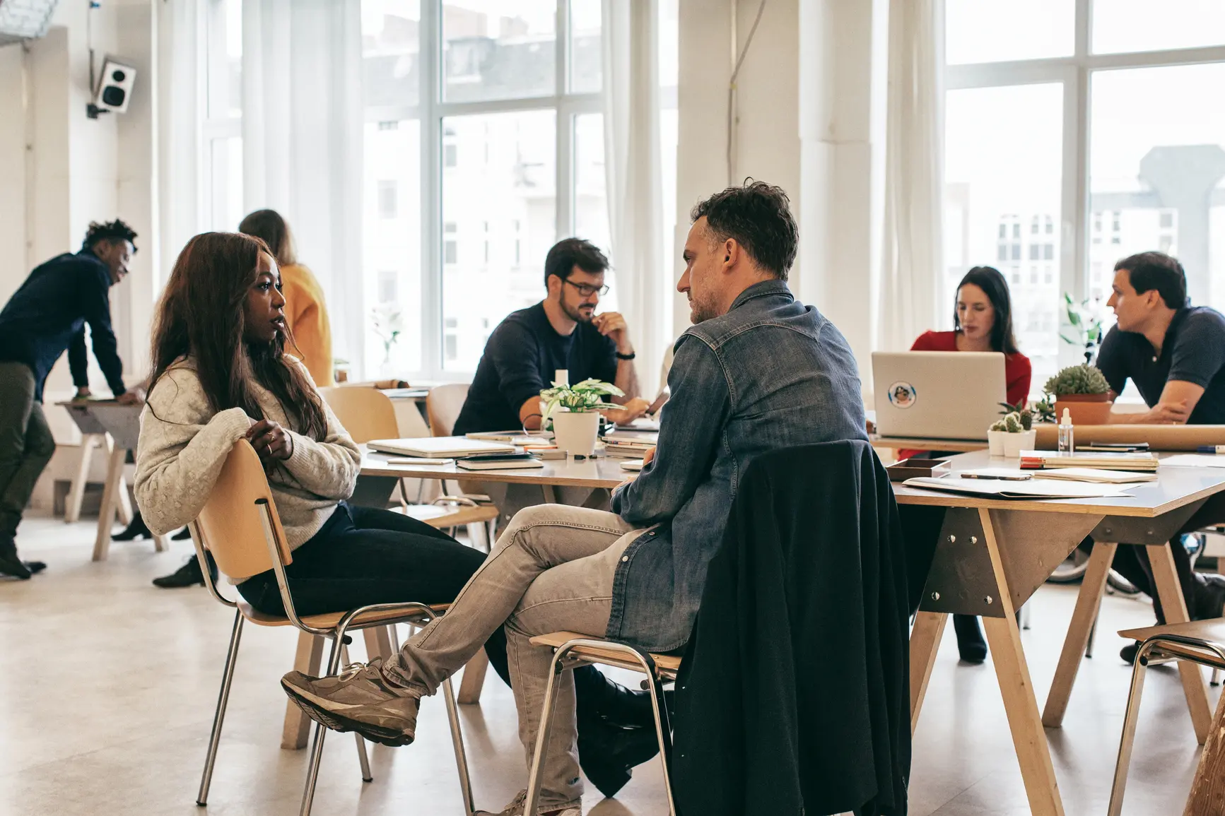 Several colleagues of an agency are talking in small teams in a bright office.