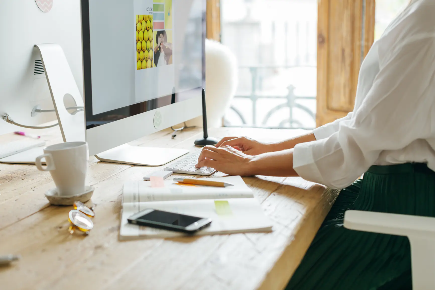 A designer works on posters at a wooden desk.