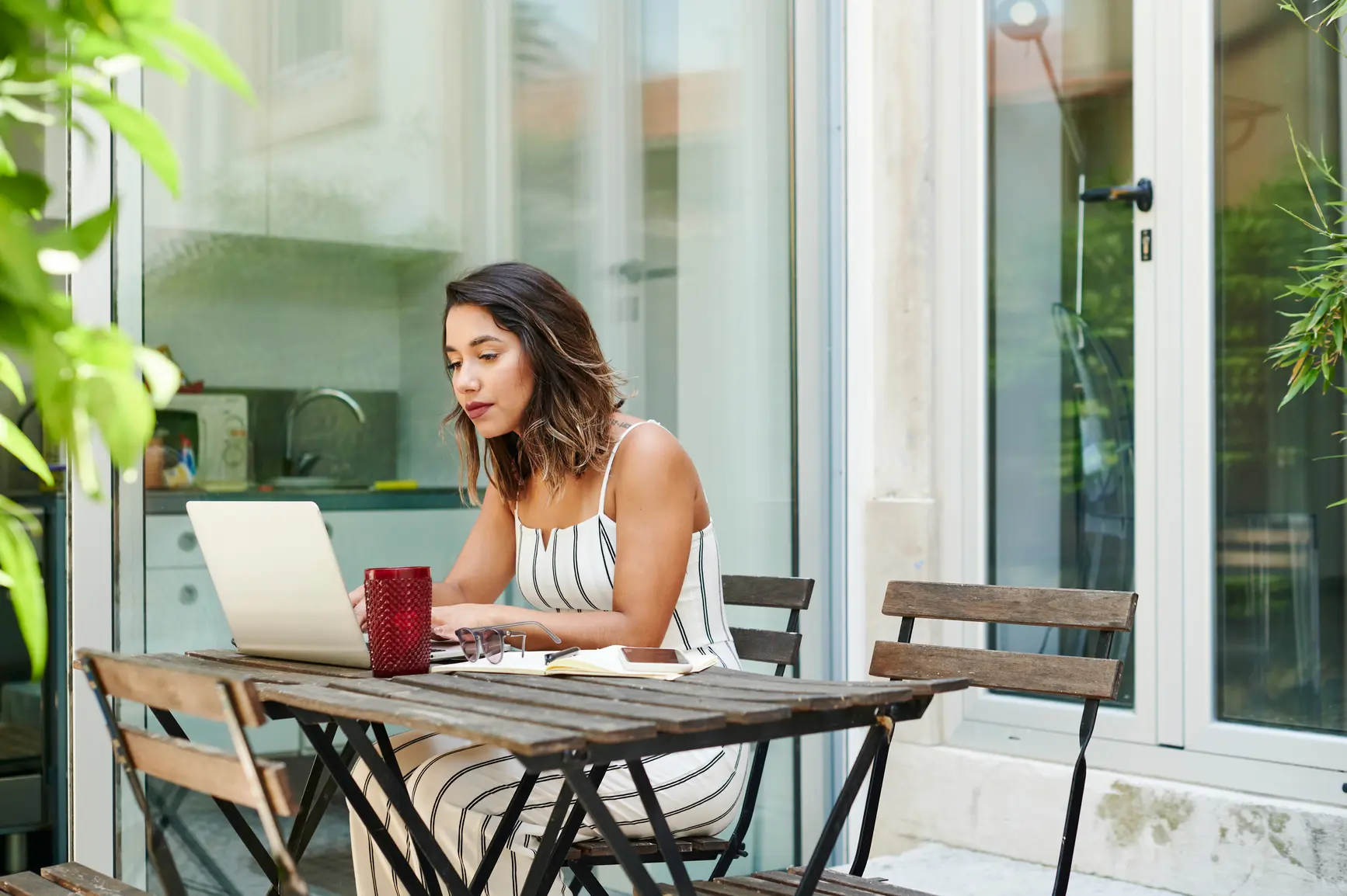 Eine junge Frau arbeitet von ihrer Terrasse aus im Home Office.