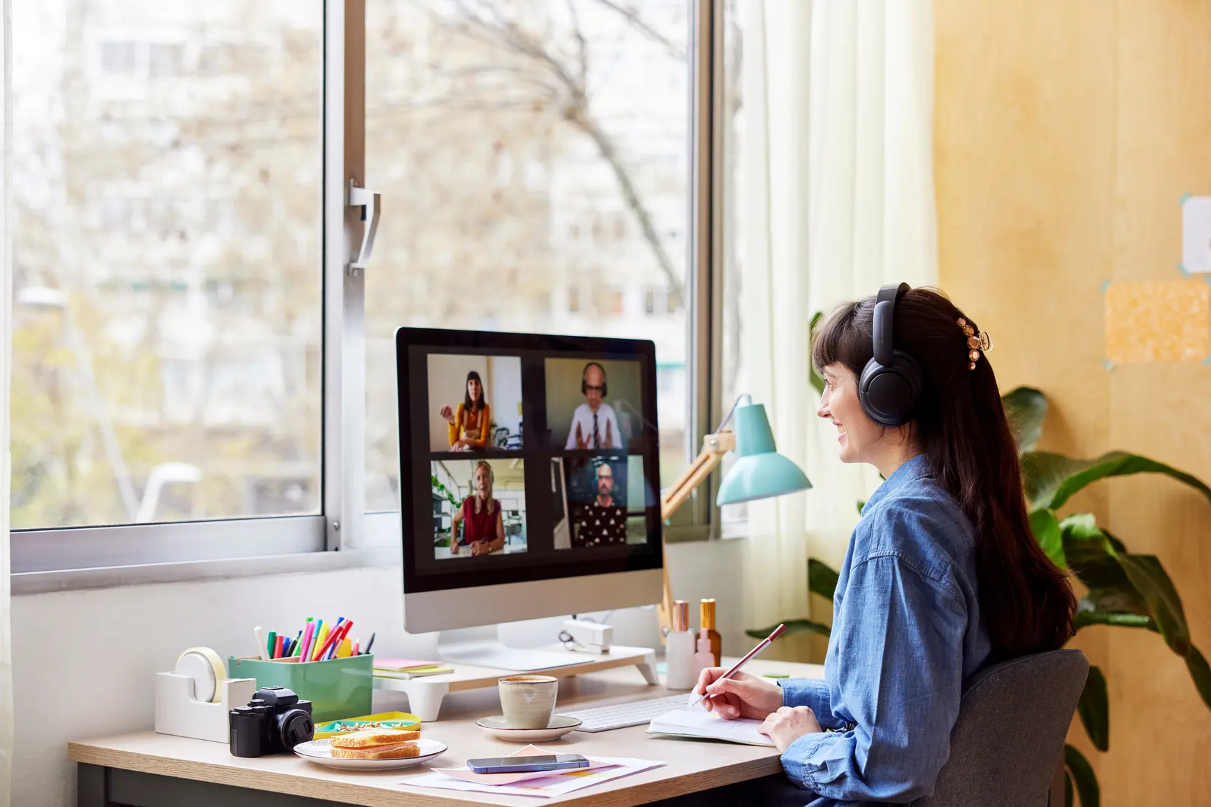 A woman sits at her desk and participates in a video conference.