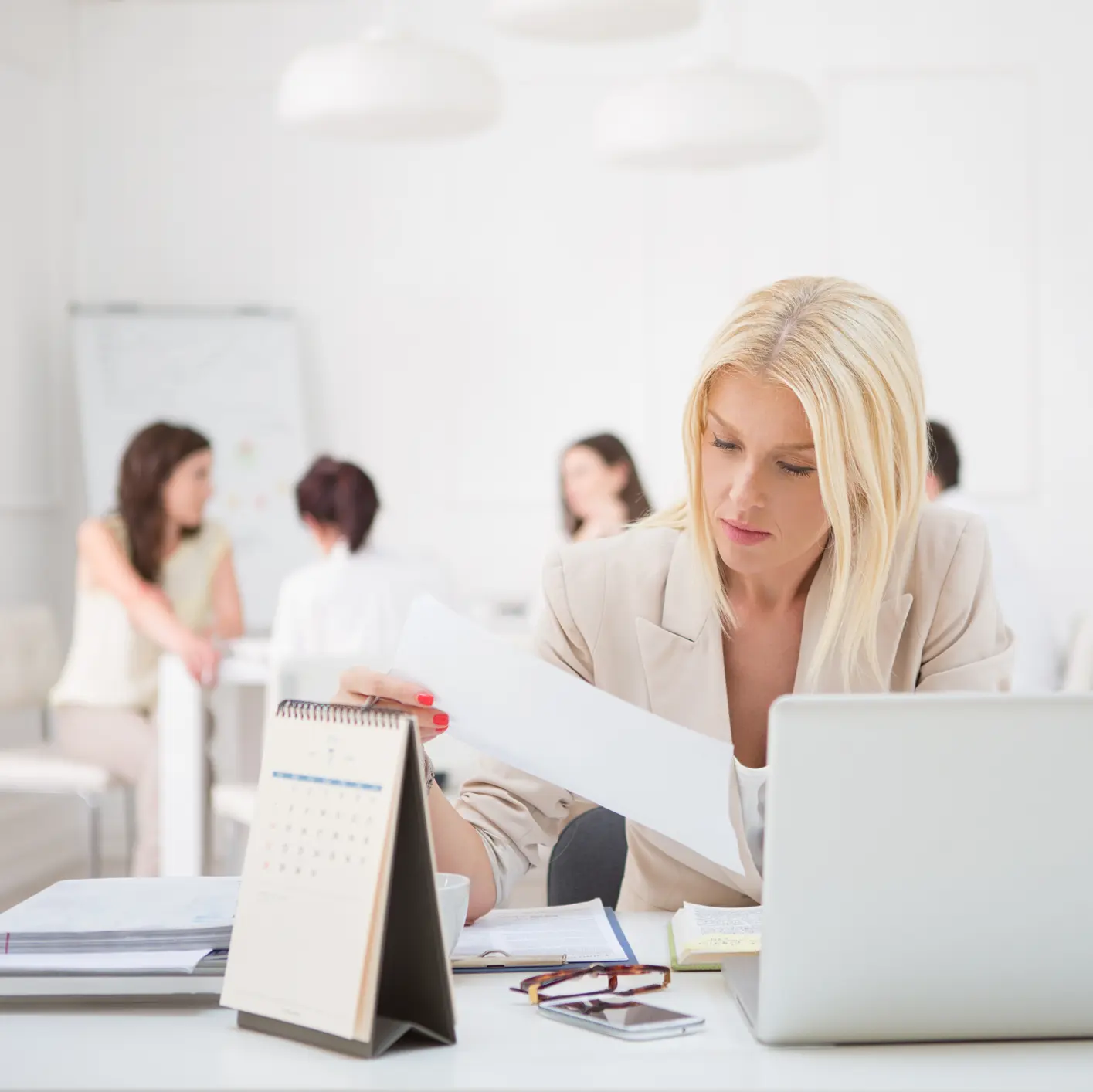 A businesswoman sits at her desk and looks at documents.