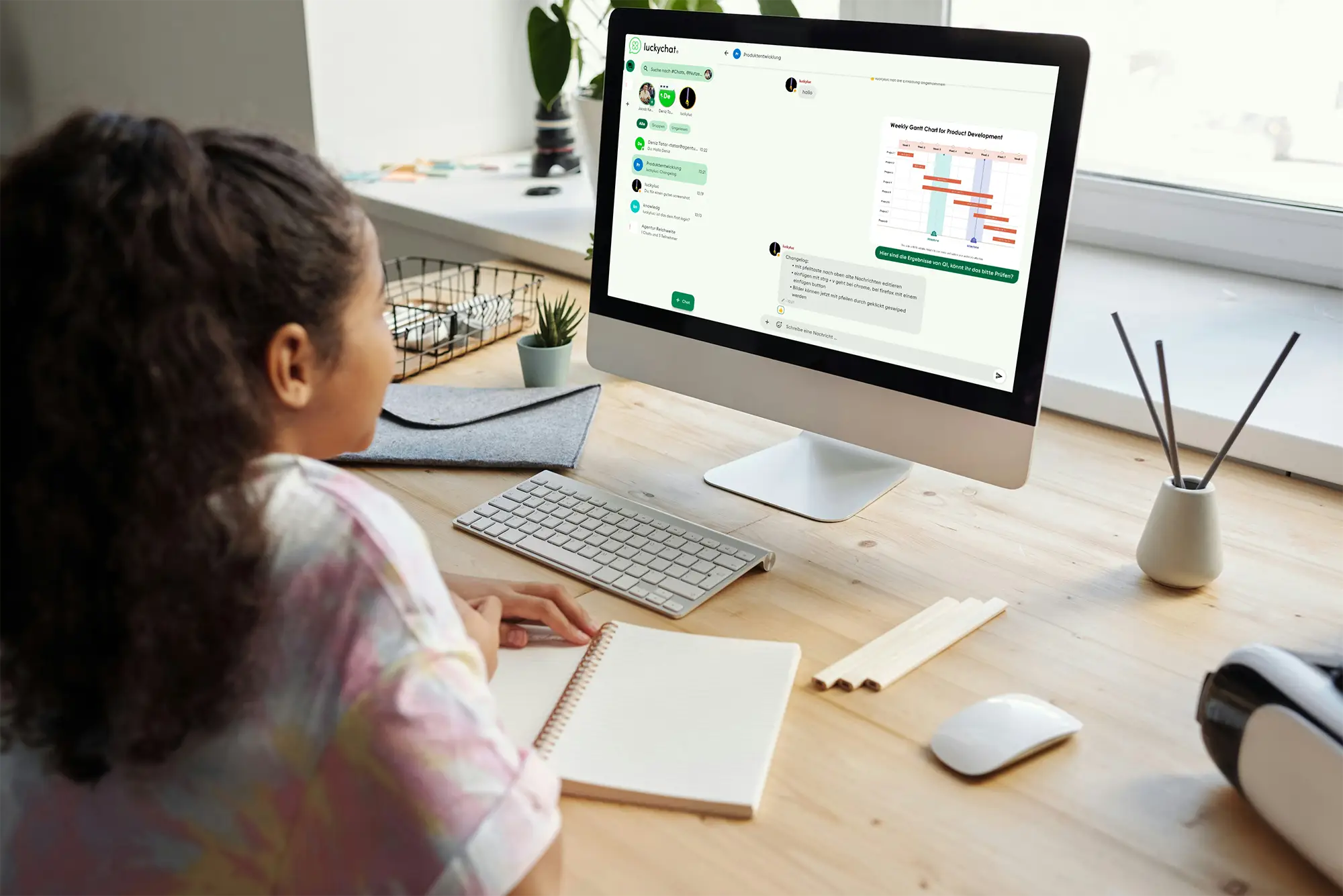 oung girl sitting at a desk with a desktop computer displaying the luckychat messaging application. She is taking notes while a chart is visible in the chat window.