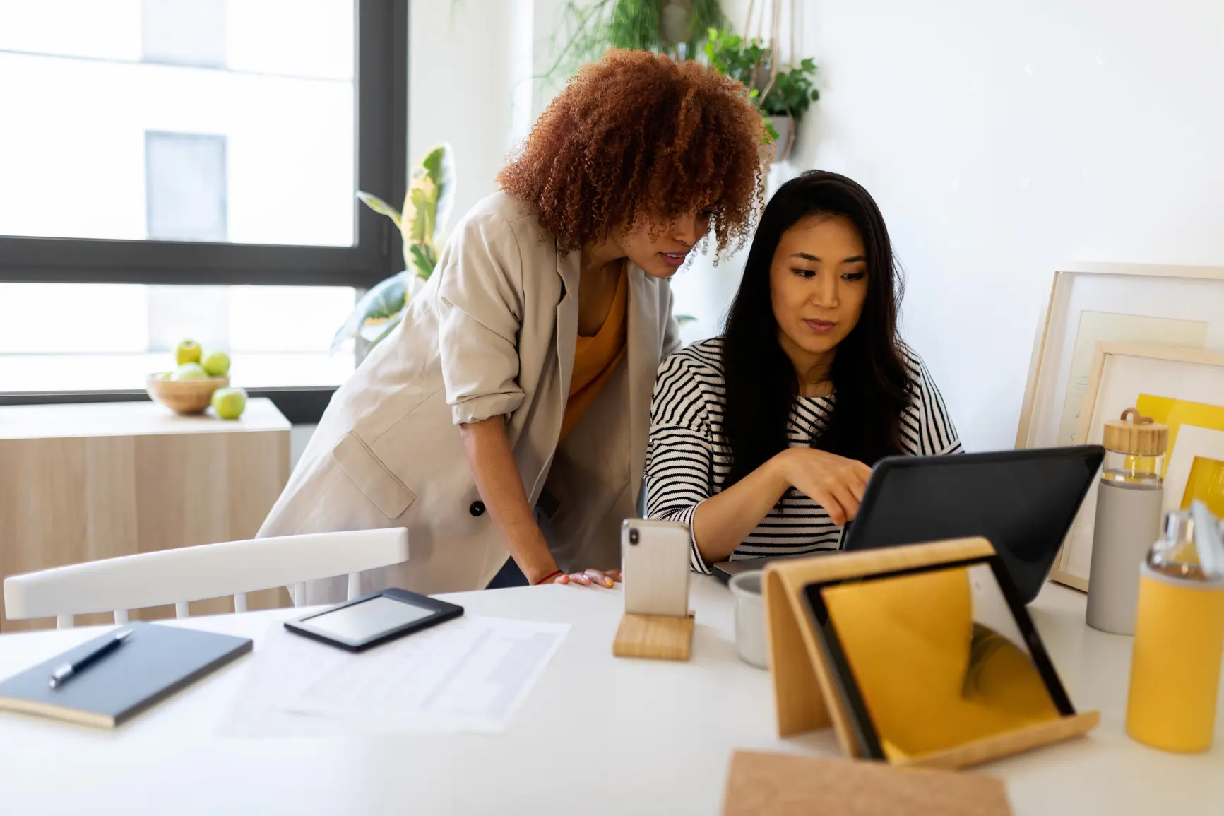 Two colleagues are working together on a tablet. Another tablet is set up in the foreground.