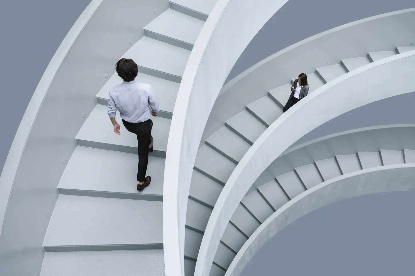 Bird's eye view of modern white spiral staircase showing two businessmen.