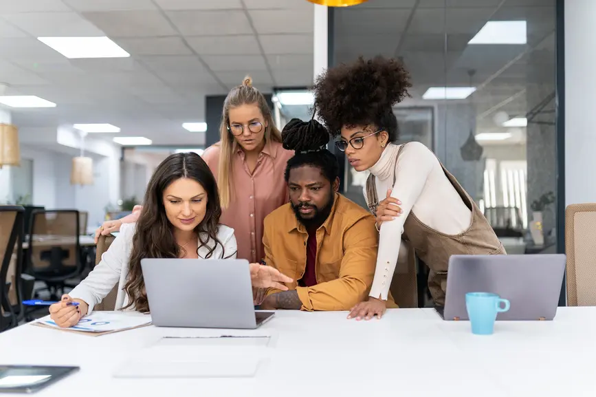 A multicultural team focuses on a laptop in the modern office.