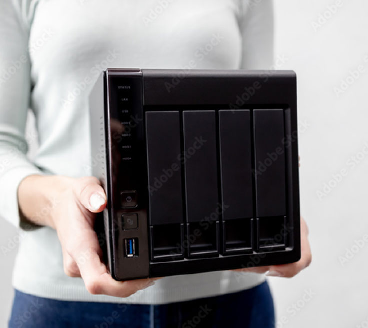 A woman holds a black NAS device in front of her body.