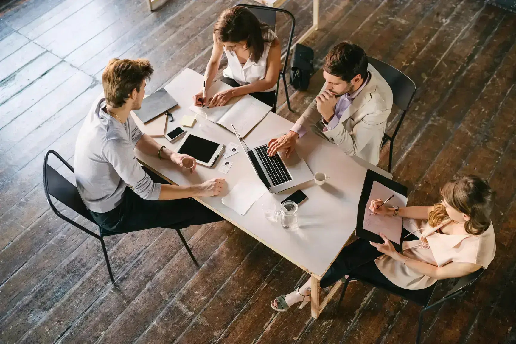 Ein junges Team sitzt gemeinsam am Tisch und bespricht zukuenftige Projekte.