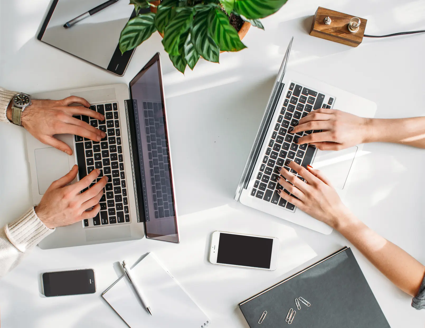 Bird's eye view of a desk with two laptops and other office items.