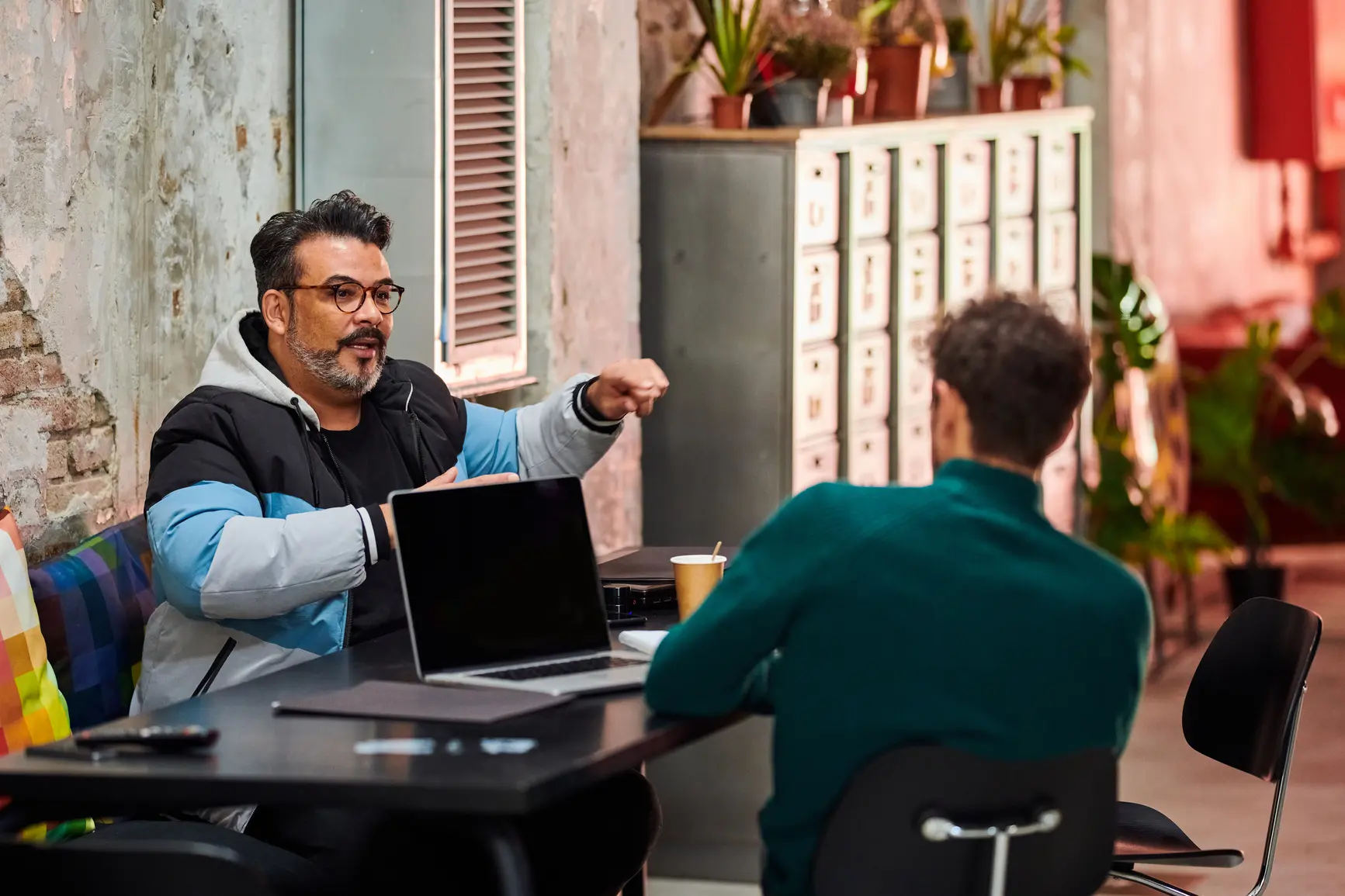 Two men talk gesticulating in a modern loft office.