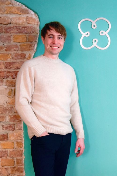 The luckycloud founder stands in front of a turquoise wall on which the luckycloud logo can be seen.
