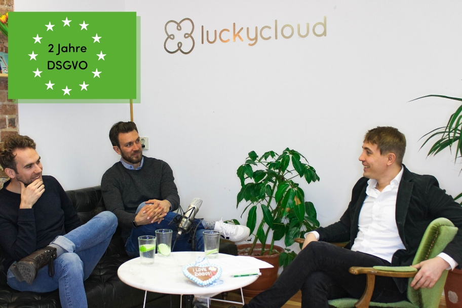 Three people are sitting on a sofa and chair, around a small coffee table, talking.