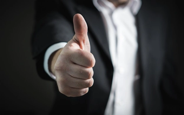 Focus on a man in a suit giving the thumbs up