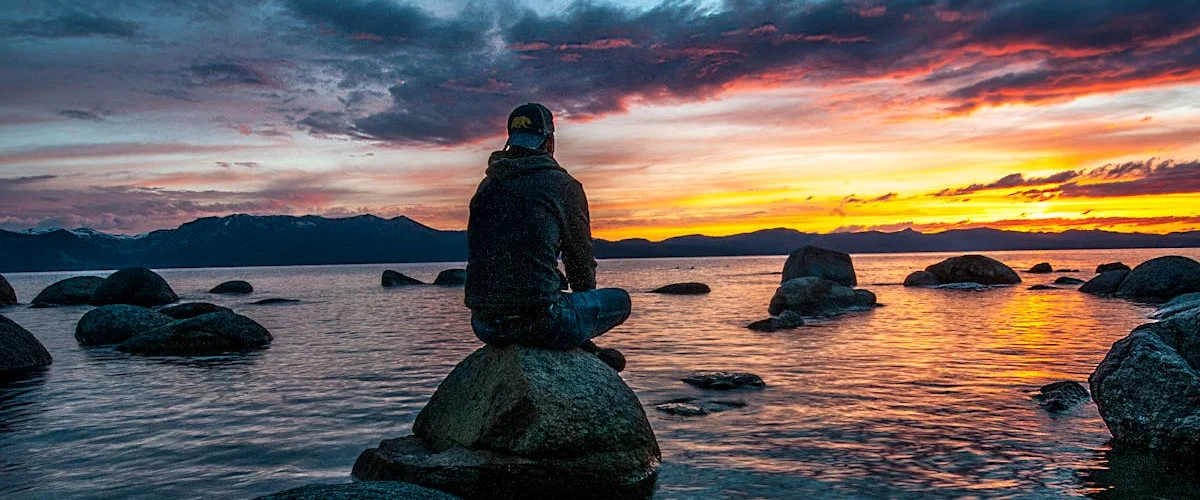 Person sitting on rocks by a body of water