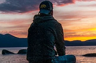 Person sitting on rocks by a body of water