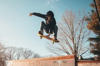 A man jumps with a skateboard in front of a blue sky.