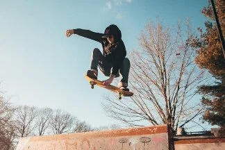 Ein Mann springt mit einem Skateboard vor blauem Himmel.